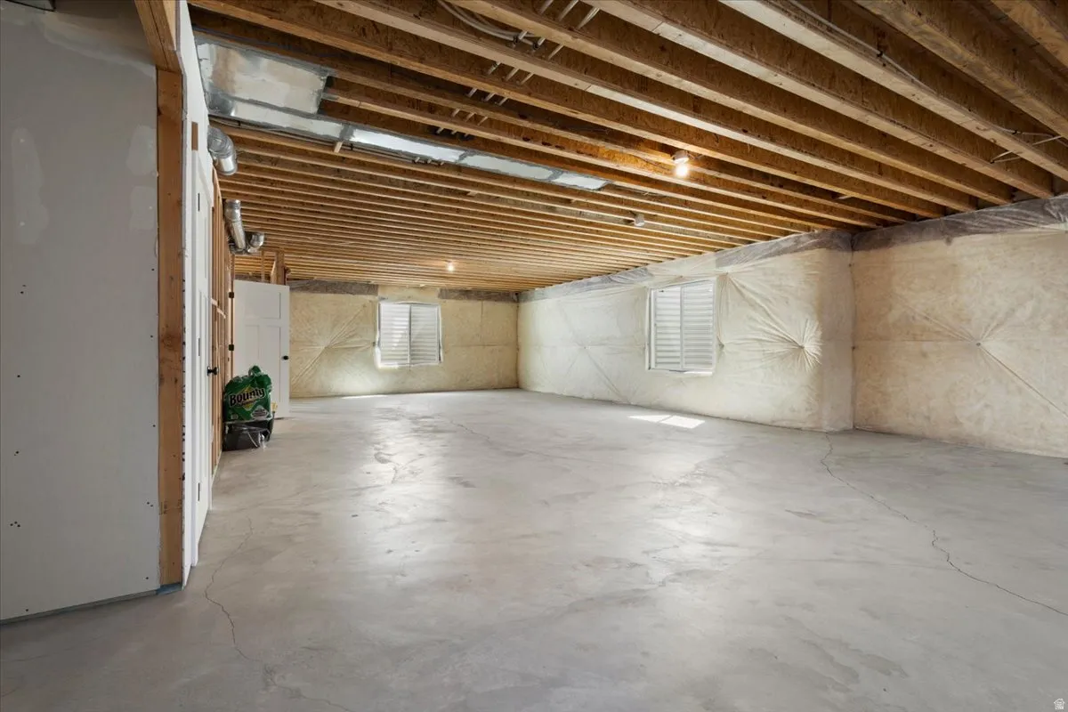 Unfinished basement offering expansive concrete flooring and exposed ceiling joists
