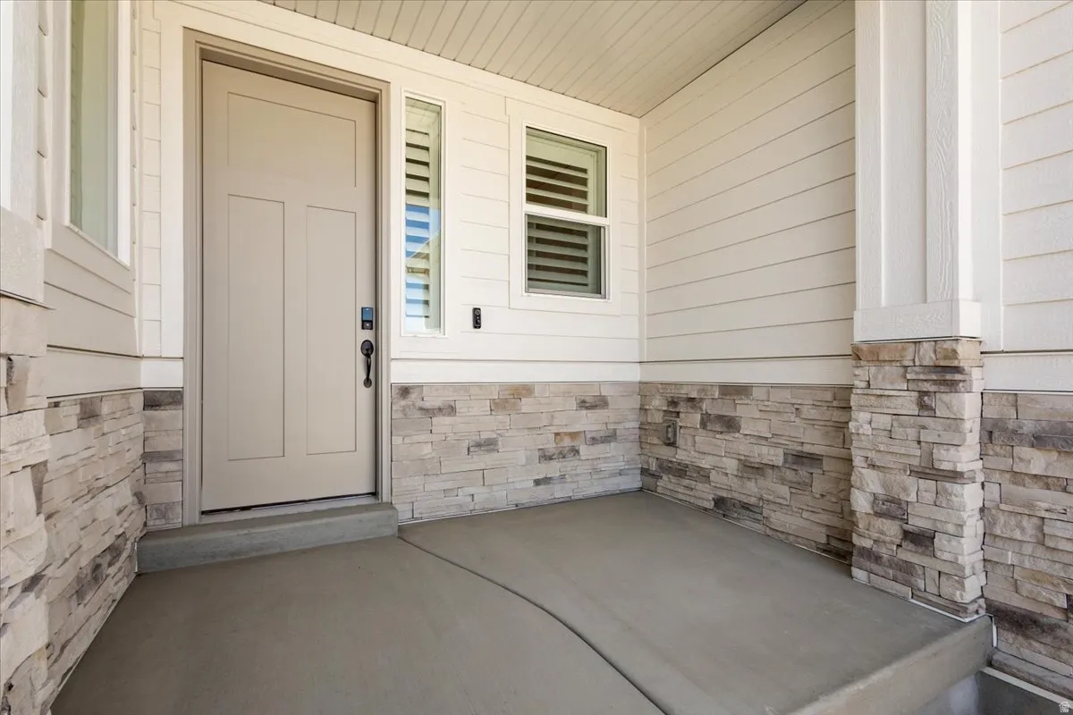 Front entry featuring a solid paneled door, sidelight, and concrete porch
