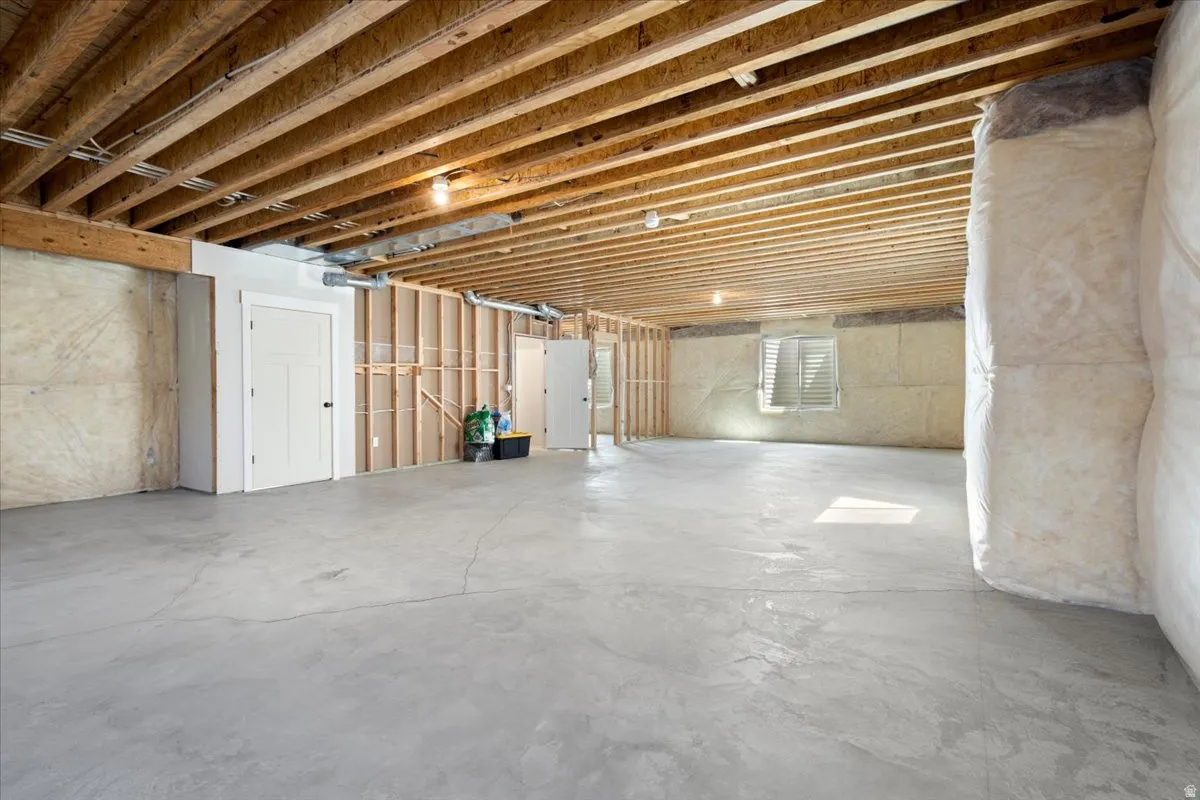 Expansive unfinished basement featuring concrete flooring and exposed joists
