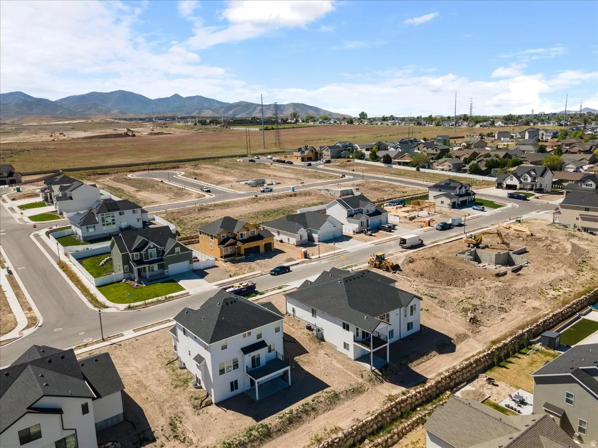New construction community featuring multiple residential properties under development, established homes with landscaped yards, and mountain scenery in the background