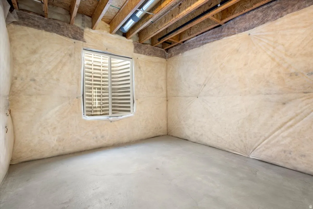 Unfinished basement space featuring exposed wood joists and subfloor, a concrete slab floor, and insulated walls