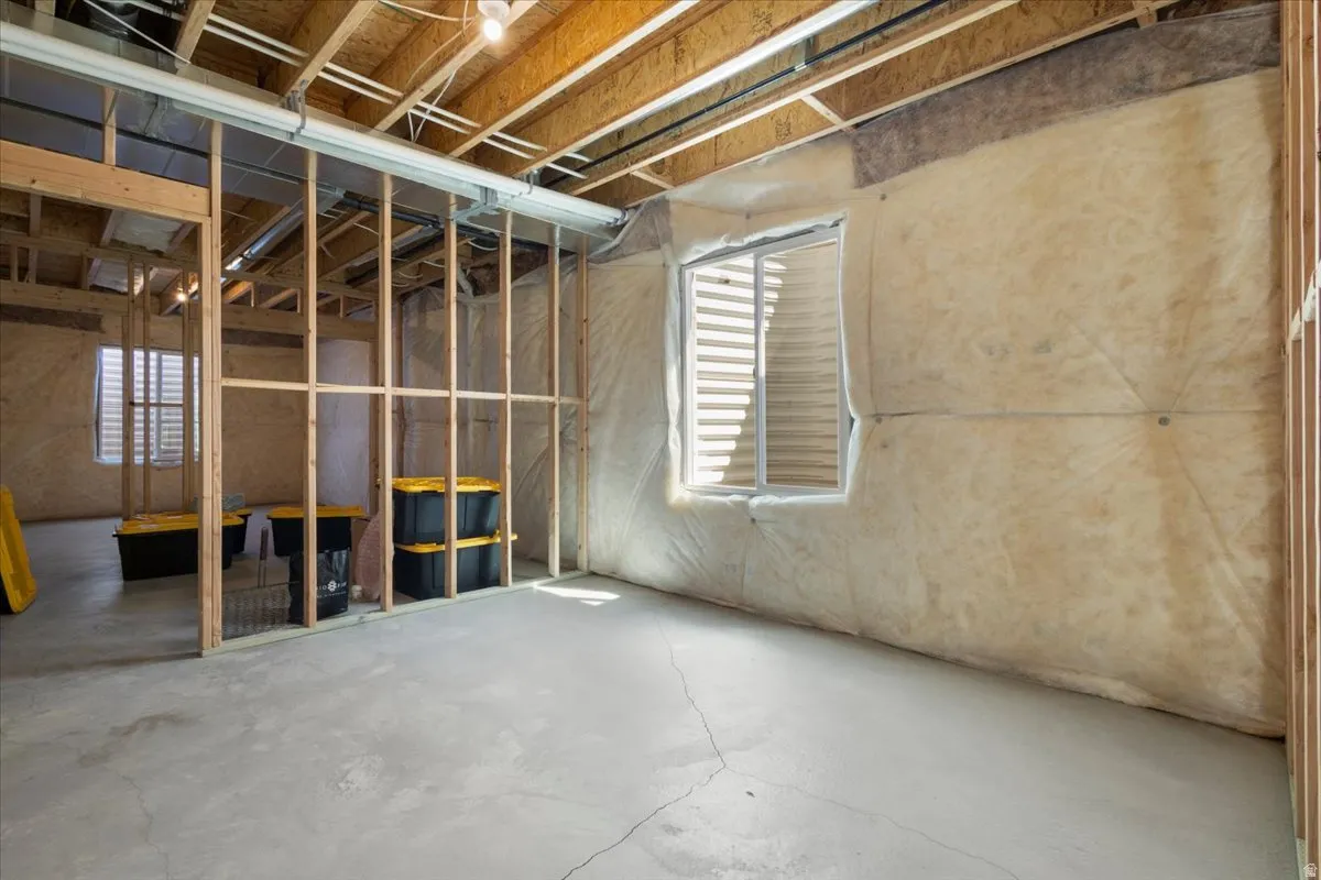 Unfinished lower level with concrete flooring, exposed wooden joists, and visible insulation