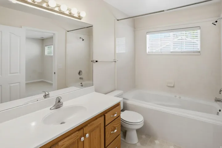 Bathroom featuring a vanity with wood-finish cabinetry and white countertop, a drop-in sink with chrome faucet, and an overhead vanity light bar