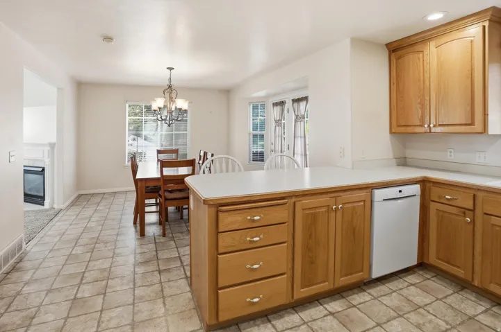 Kitchen featuring wood cabinetry, white countertops, and integrated dishwasher