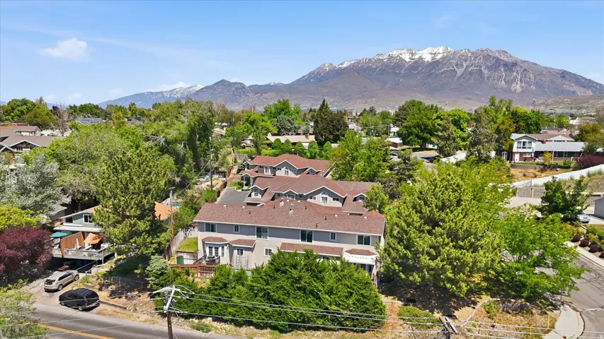 Multi-level townhome-style property featuring a neutral exterior, private balconies, and a mountain backdrop