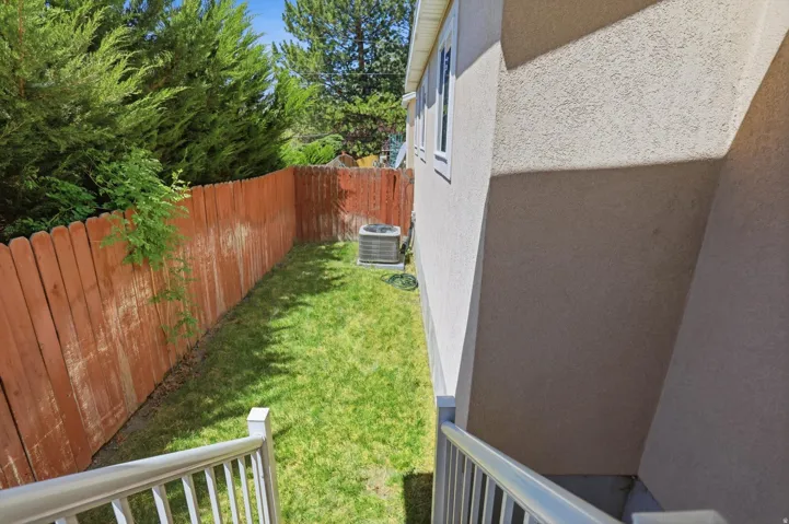 Private side yard with a manicured lawn, wood picket fencing, and mature perimeter trees
