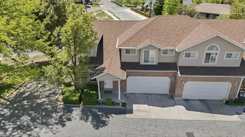 Townhome exterior featuring a brown shingle roof, brick facade accents, and two prominent dormer windows