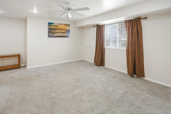 Spacious carpeted room featuring a ceiling fan with integrated lighting, recessed lighting, baseboards, and window treatments