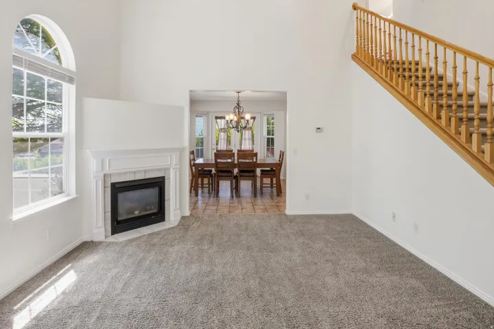 Living area featuring a fireplace with a white mantel, an arched window, and a carpeted floor