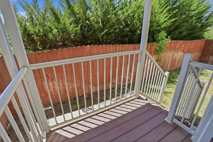 Outdoor deck with composite wood-finish flooring, white railings, and steps descending to a grassy area