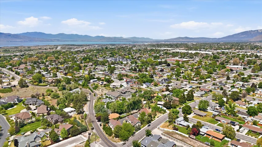 Expansive residential area featuring numerous single-family homes, mature trees, and a distant lake with surrounding mountains