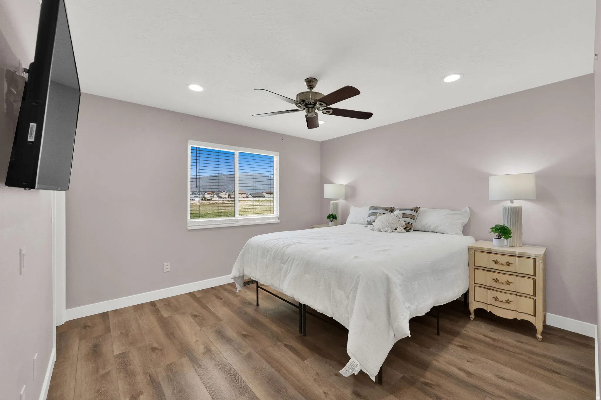 Spacious room featuring wood-finish flooring, a ceiling fan with light, and recessed ceiling lights