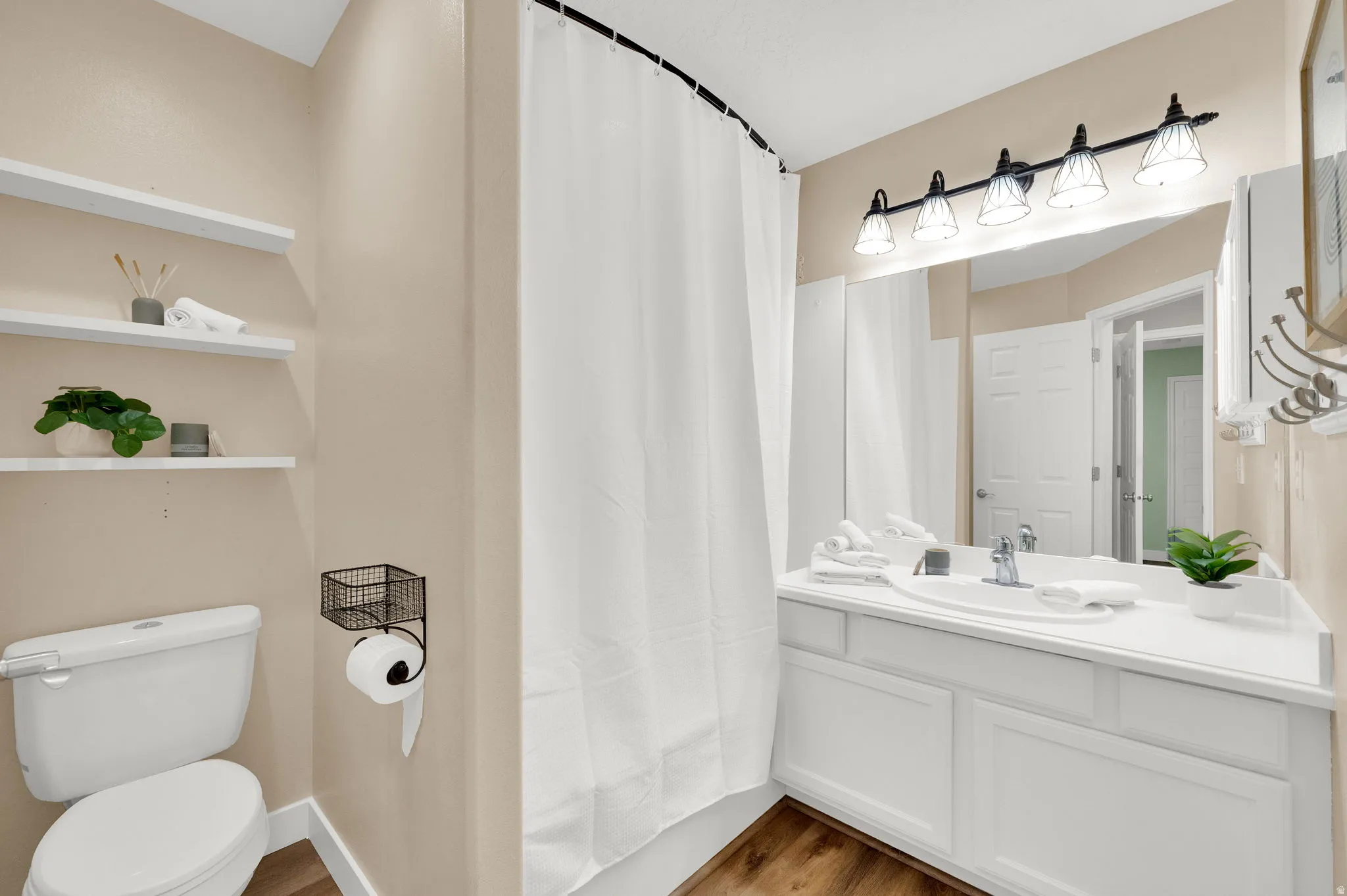 Bathroom featuring a white vanity with integrated sink, white cabinetry, and a large wall-mounted mirror