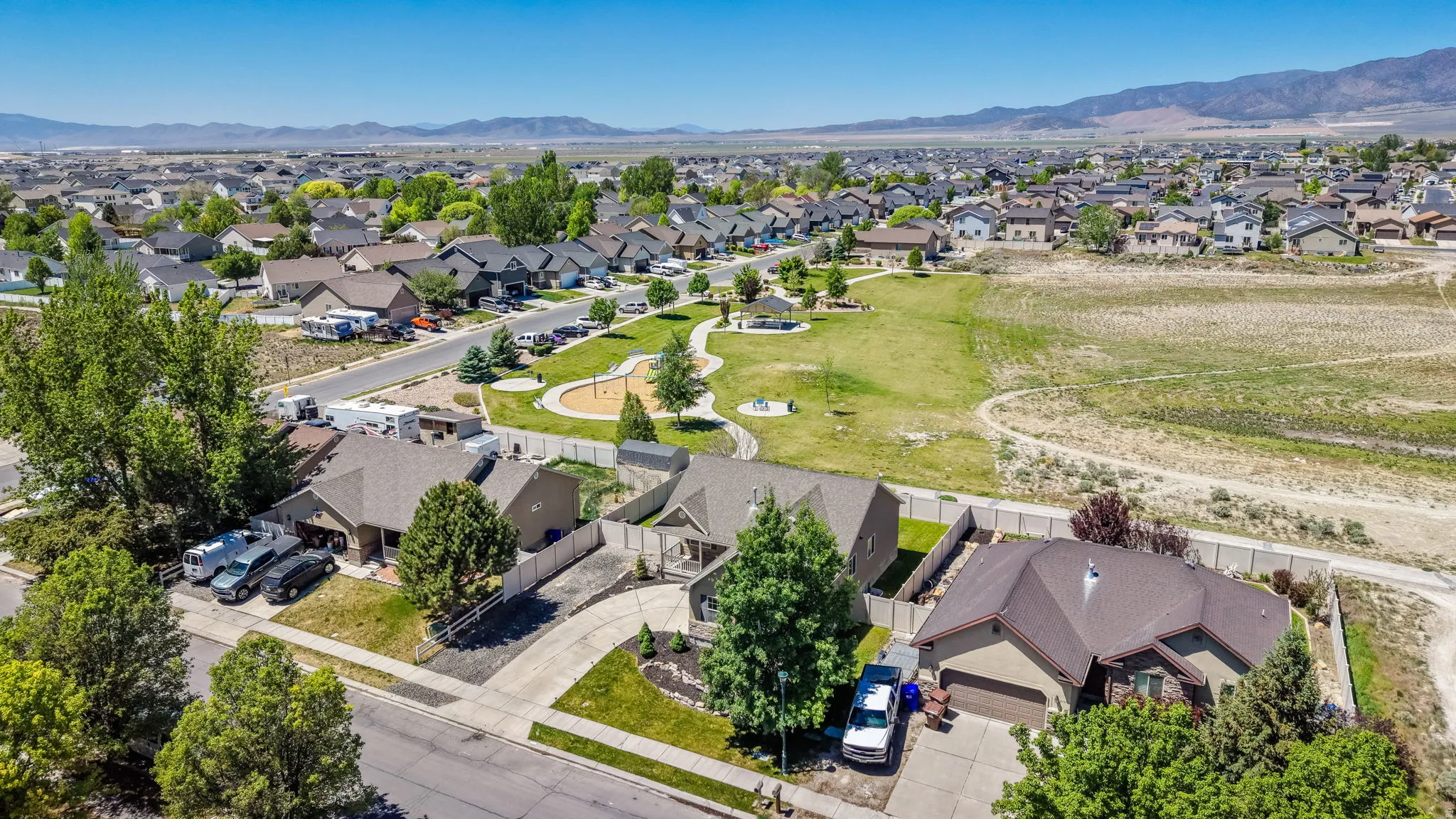Aerial perspective of a residential neighborhood featuring single-story homes with attached garages, paved driveways, and mature landscaping