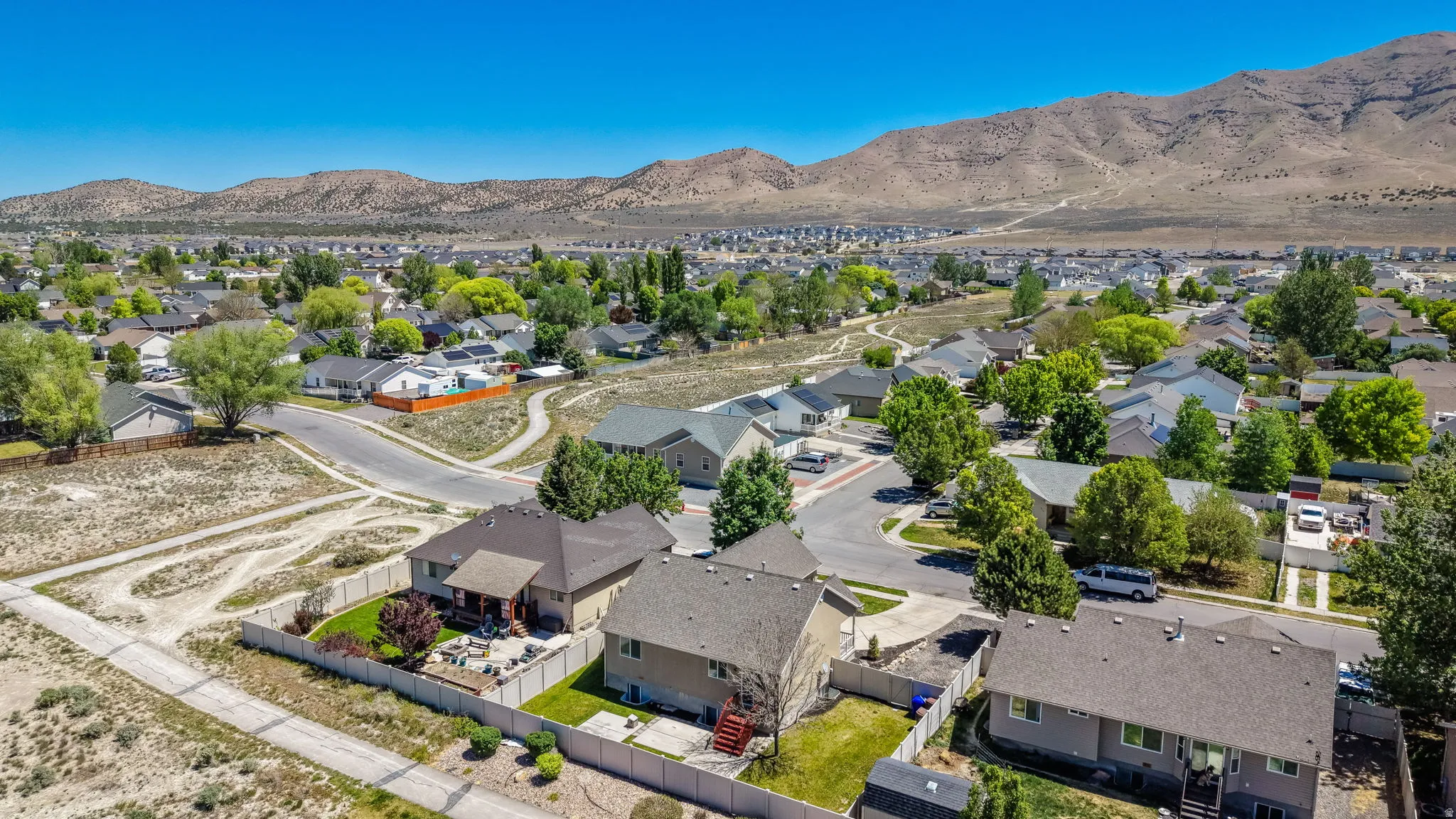 Expansive residential neighborhood with mature trees and paved roads, set against a backdrop of distant mountains