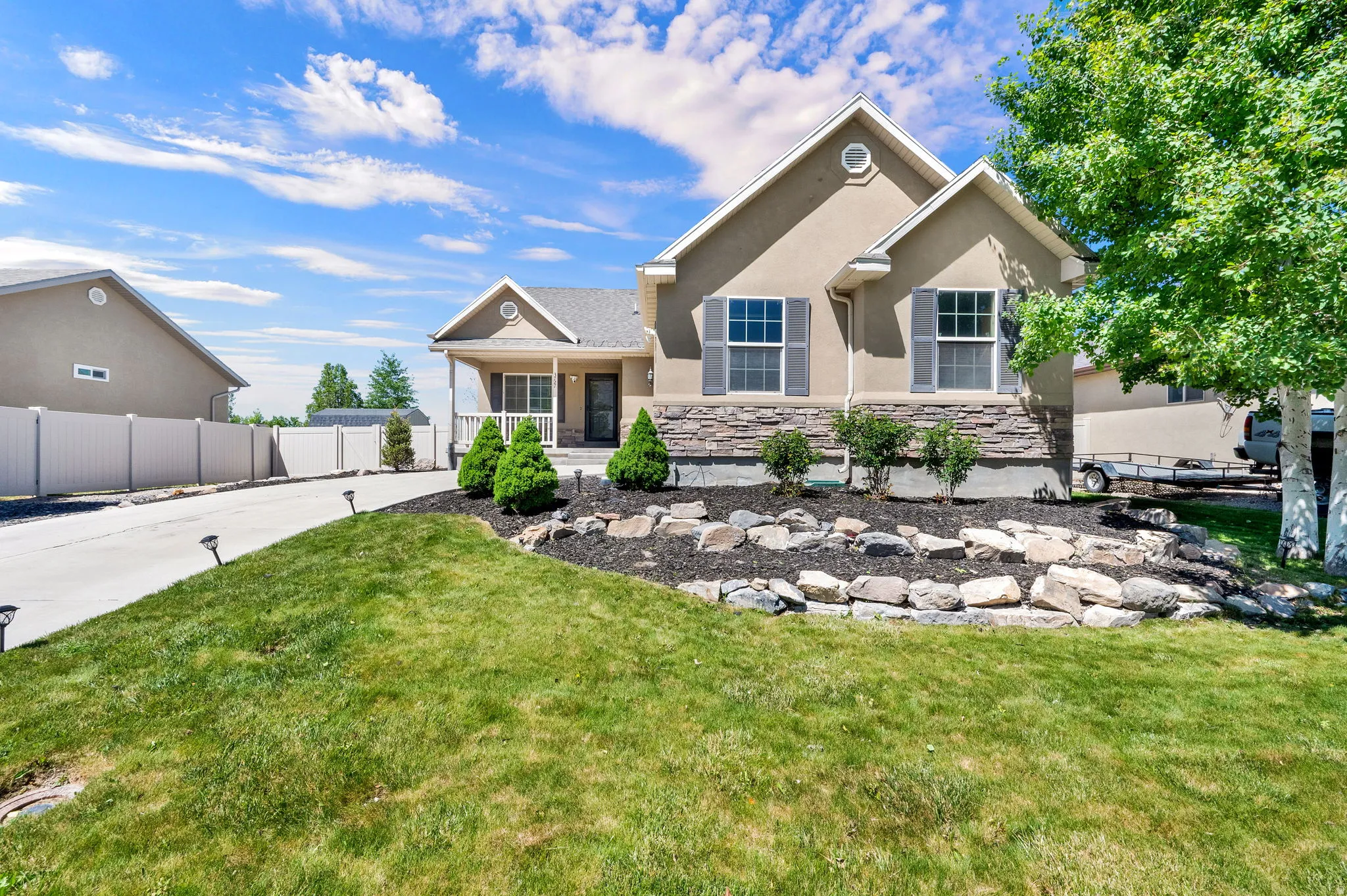 Stucco exterior with a stone veneer foundation and gray shutters