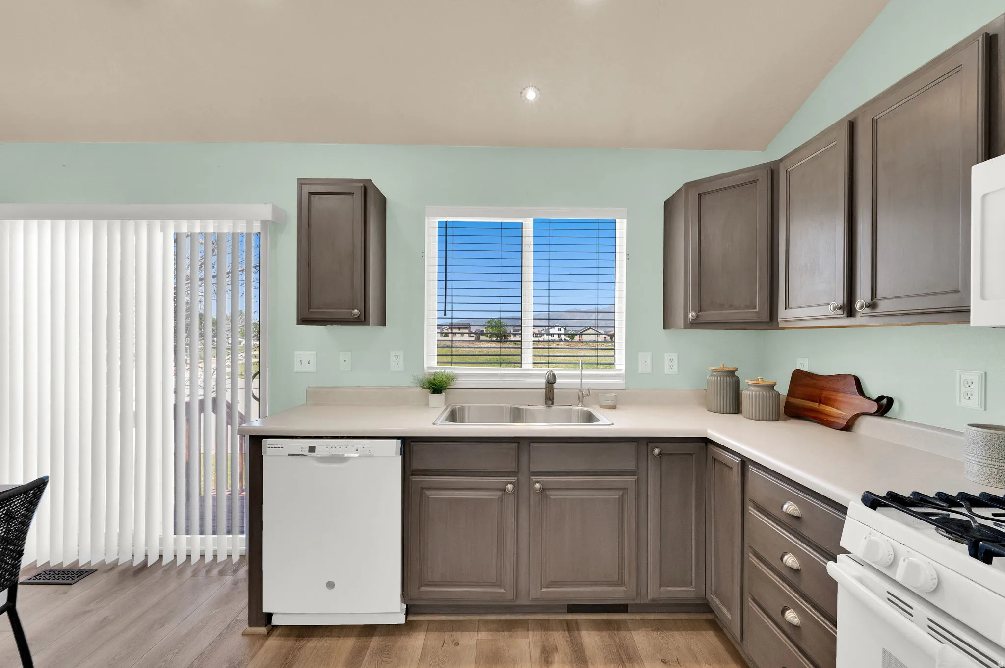 U-shaped kitchen featuring wood-finish flooring, light-toned countertops, and brown cabinetry