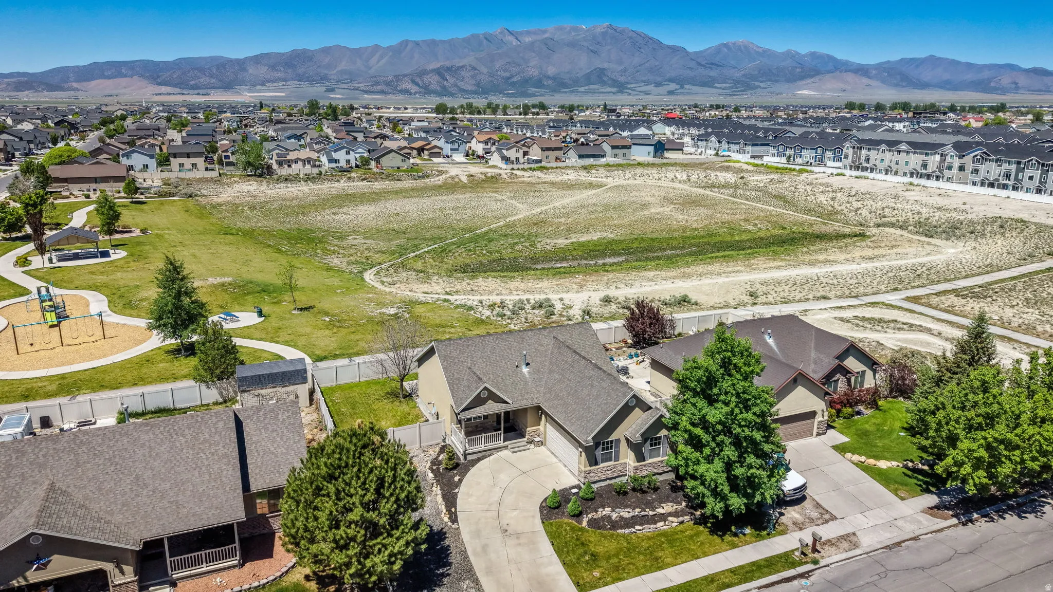 Aerial perspective showcasing a residential property with a paved driveway, mature trees, and landscaped shrubbery