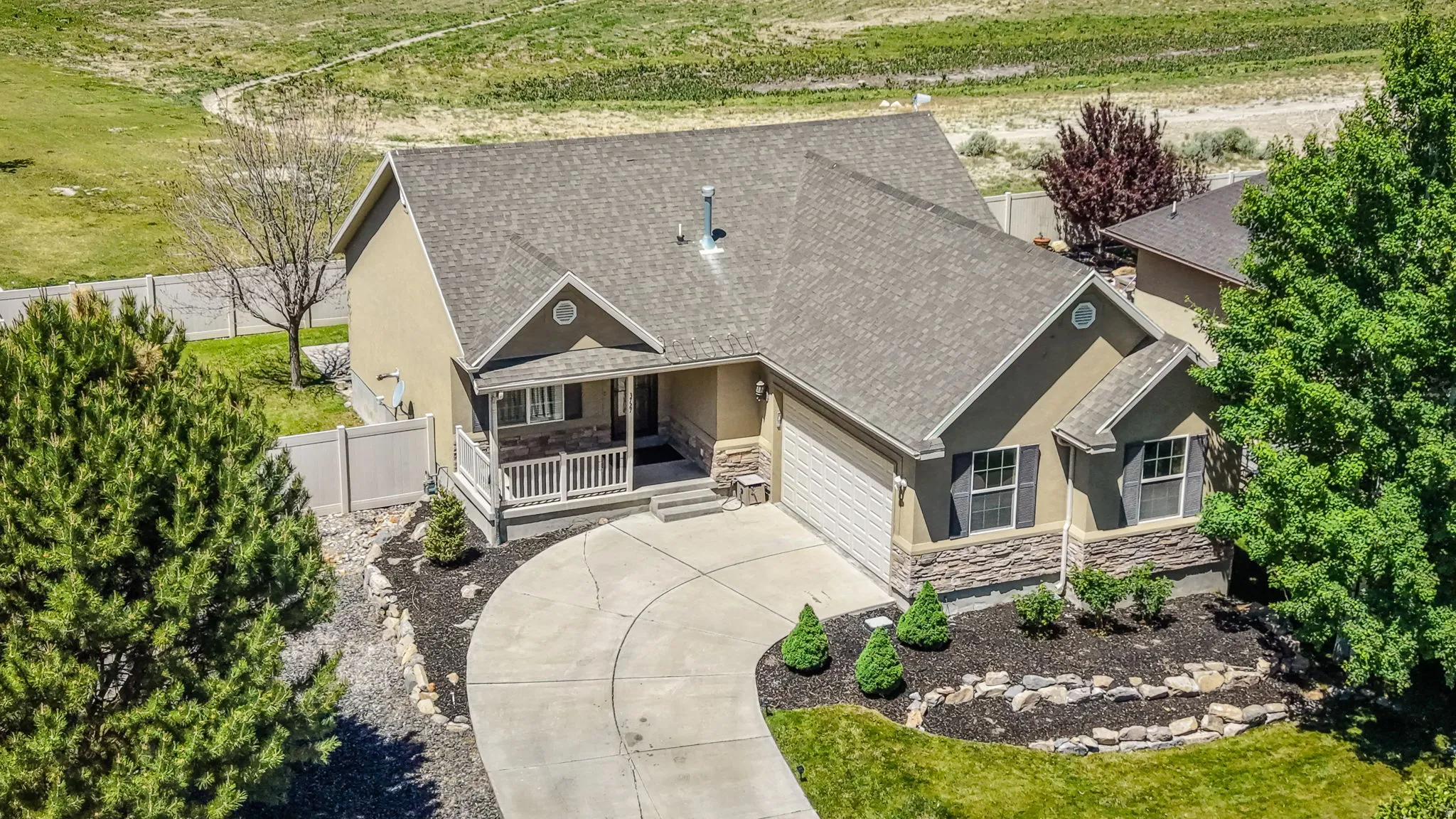 Single-story residence featuring a gray asphalt shingle roof, stucco and stone veneer exterior, an integrated garage, and a covered front porch with white railings