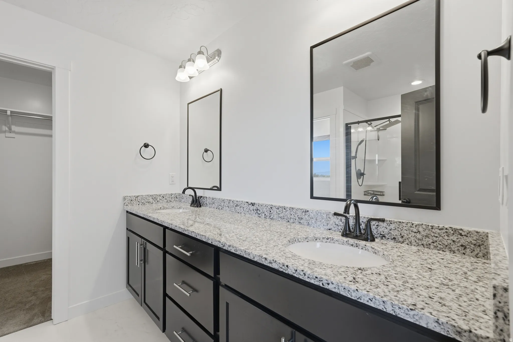 Dual vanity with granite-style countertop, undermount sinks, and dark cabinetry