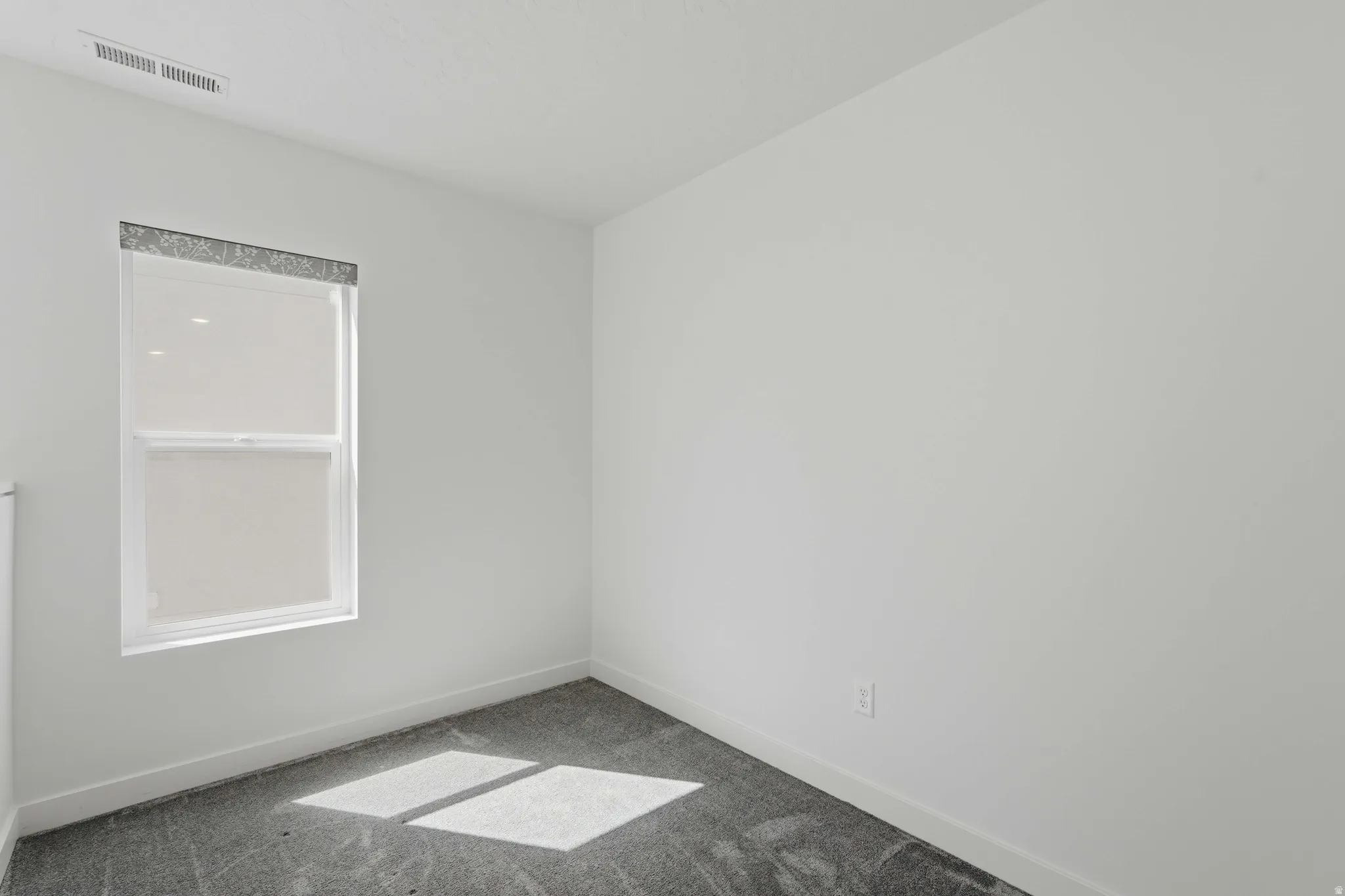 Bright room featuring neutral wall tones and a single window with a roller shade