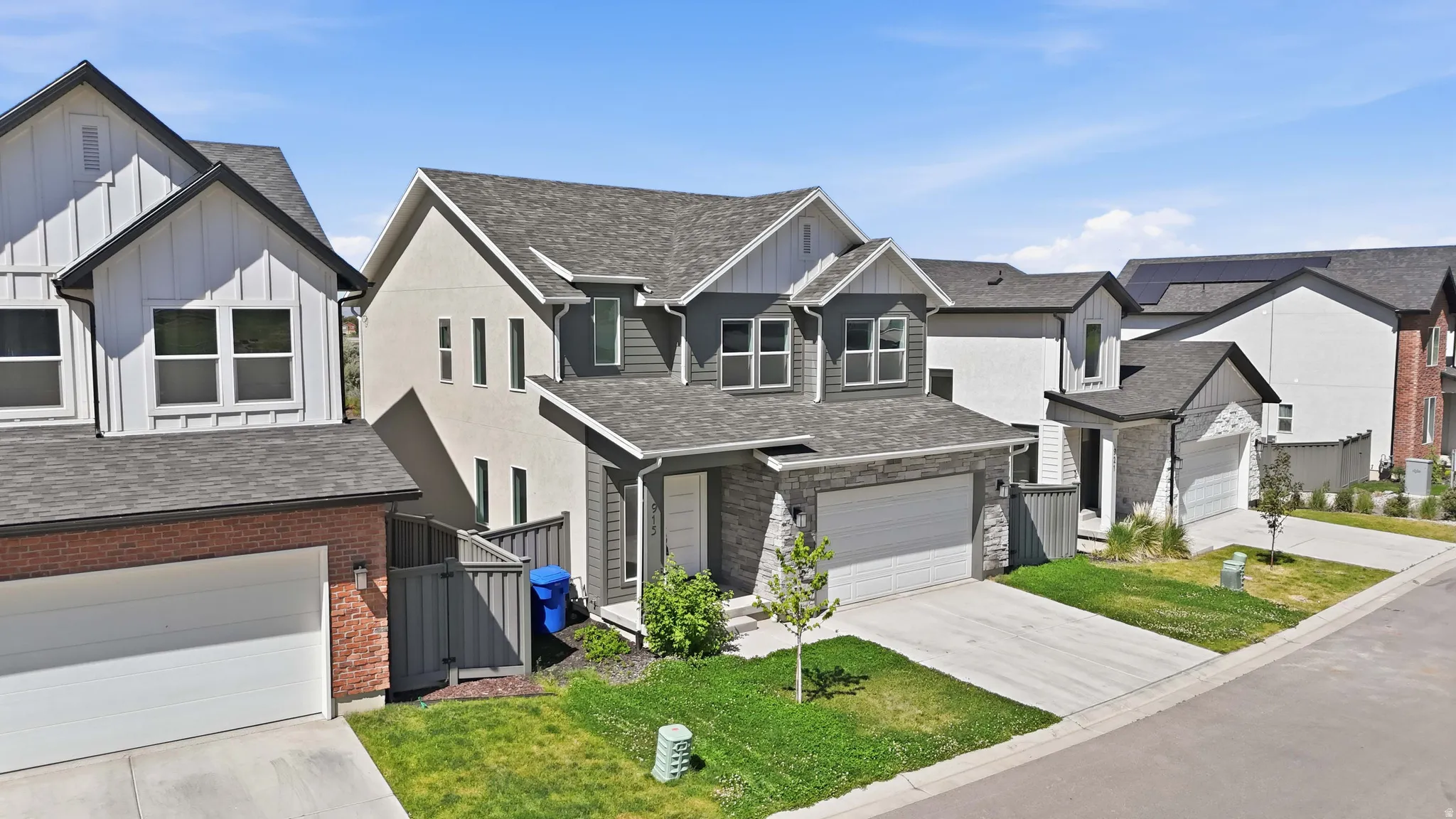 Contemporary-style home featuring a two-car garage with a white door, light gray stone accents, and dark gray siding
