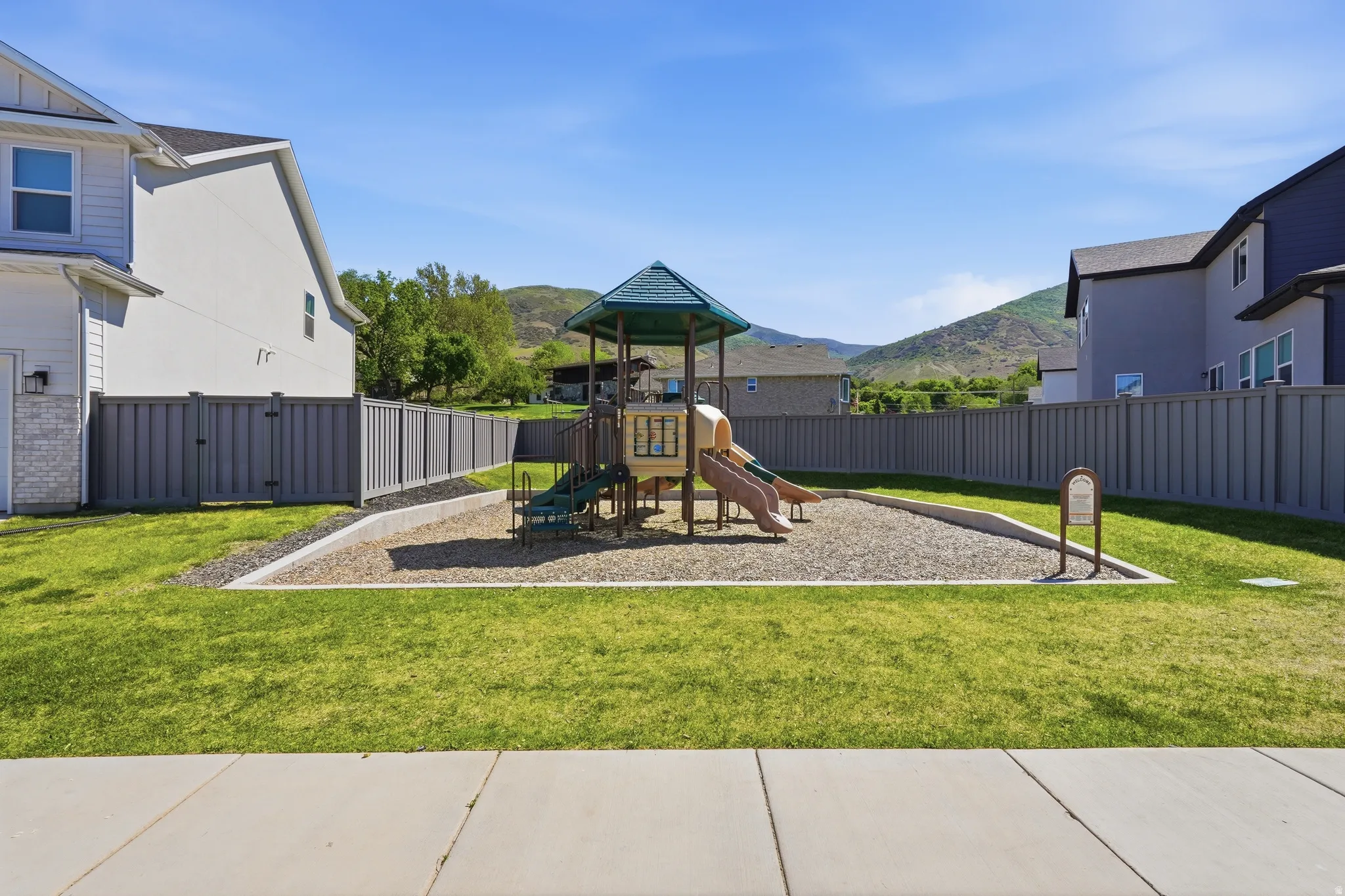 Community playground featuring a multi-level play structure with slides and climbing elements, set on a gravel base