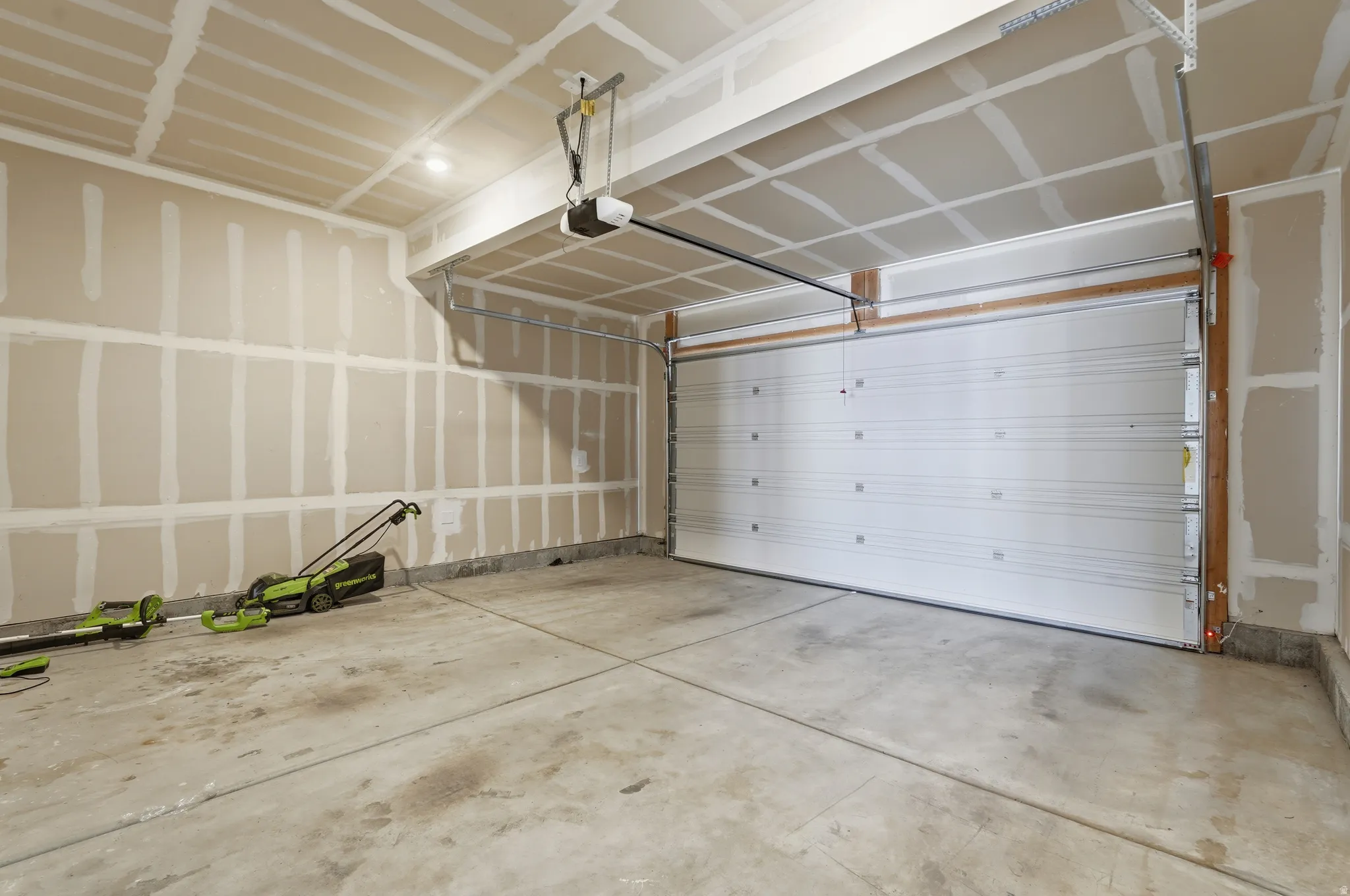 Spacious garage featuring a concrete floor, ceiling-mounted lighting, and an overhead garage door