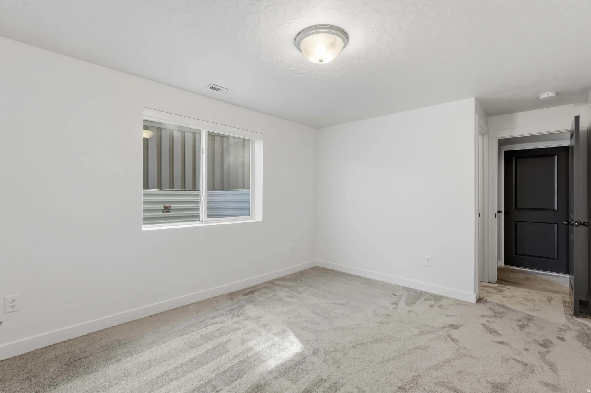 Room featuring light gray carpeting, crisp white walls, and a recessed window