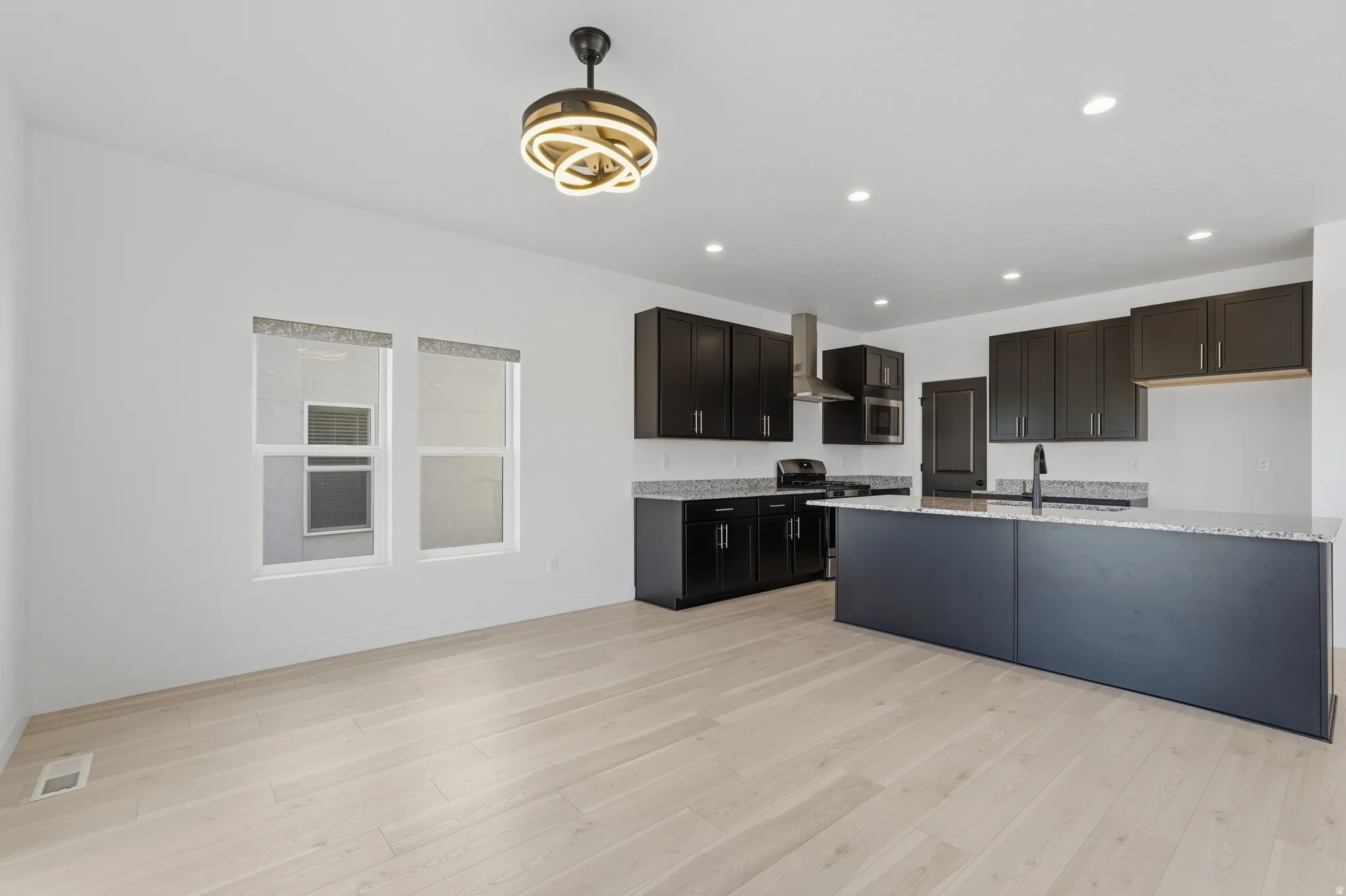 Open-concept kitchen and living area featuring light wood-finish flooring, white walls, and recessed lighting
