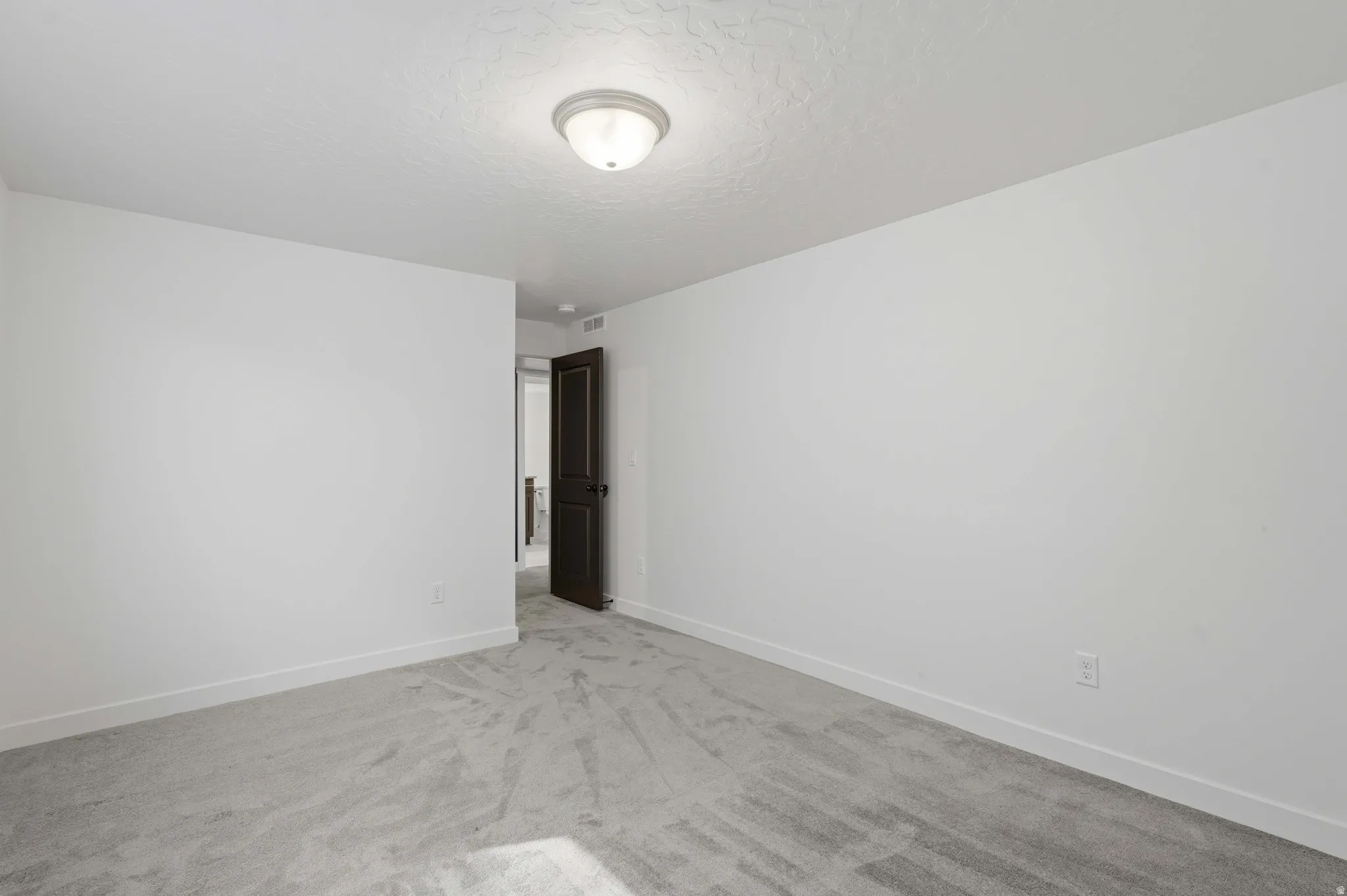 Neutral white walls with matching baseboards, textured ceiling, and a flush mount ceiling light