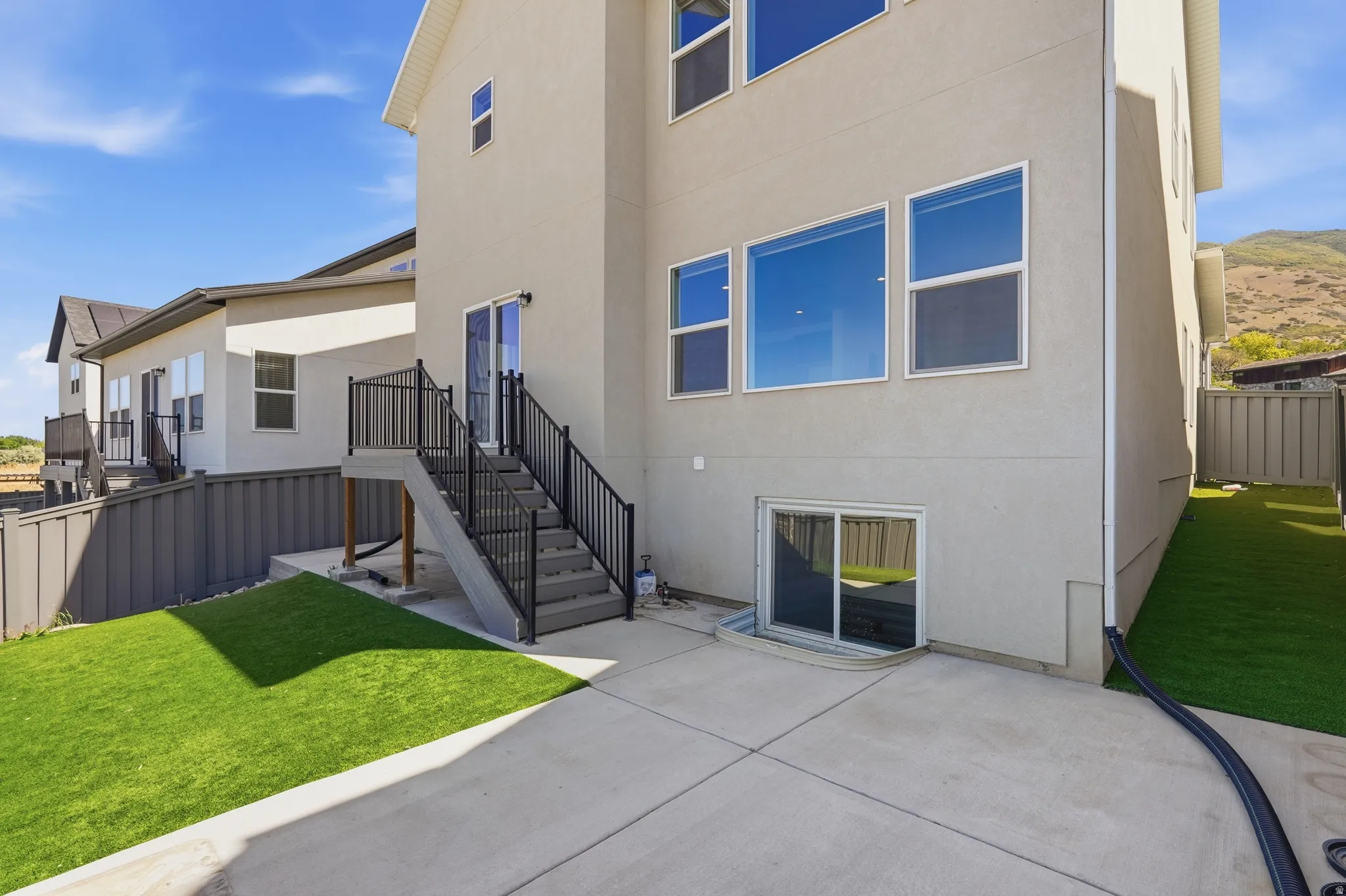 Rear exterior featuring a concrete patio and artificial turf areas