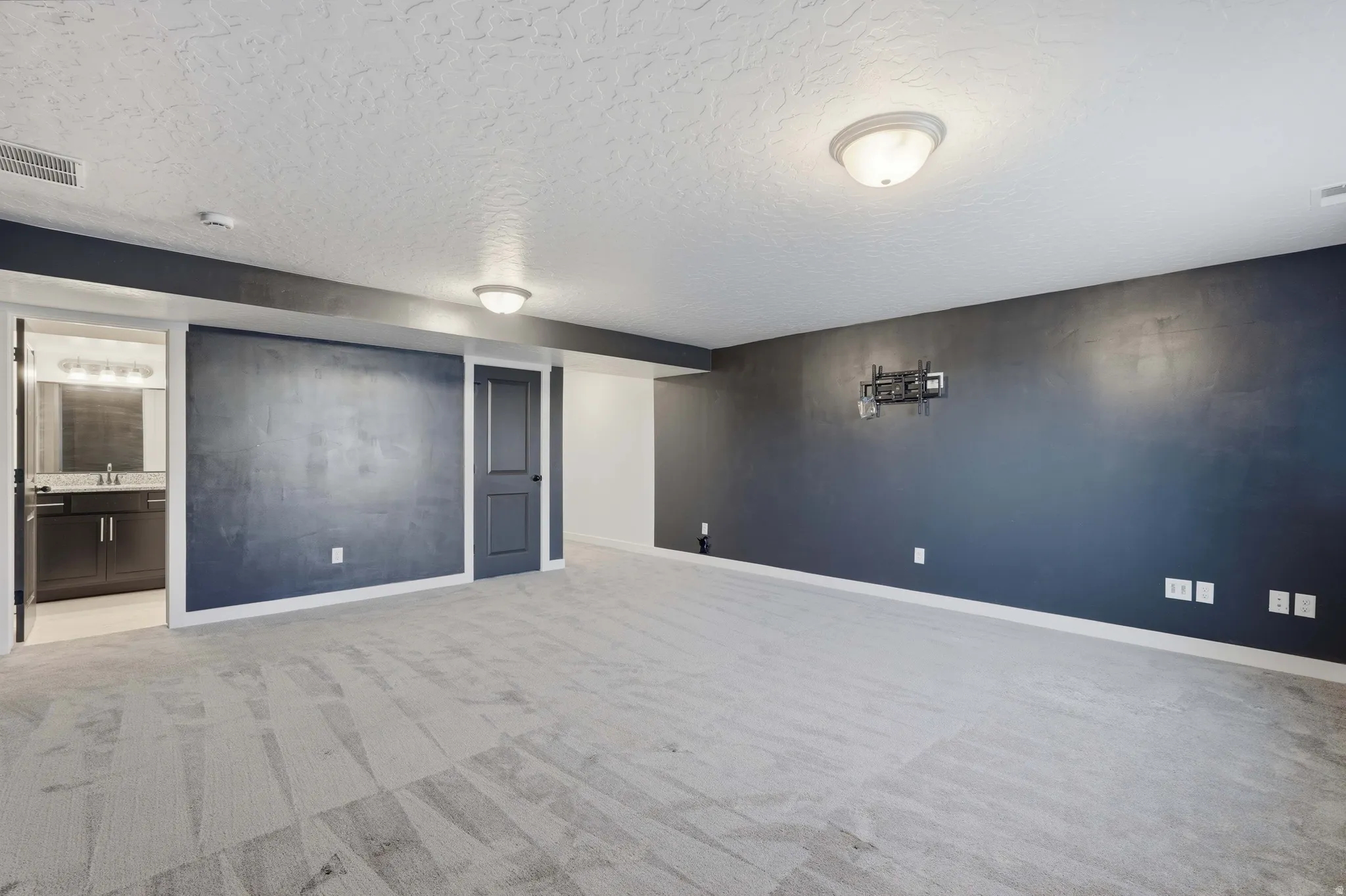 Spacious room featuring patterned carpeting, recessed lighting, and a dark accent wall