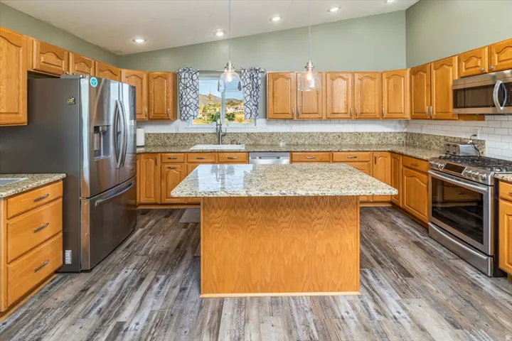 Kitchen featuring wood cabinetry, light-toned granite countertops, and a central island