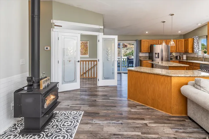 Spacious open-concept living area featuring wood-finish flooring, a freestanding wood-burning stove, and vaulted ceilings