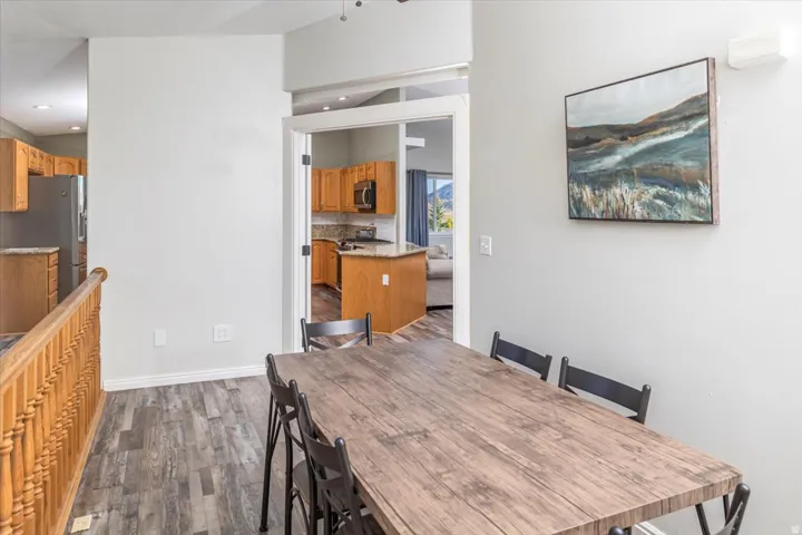 Spacious dining area featuring wood-finish flooring, light grey walls, and a baluster railing