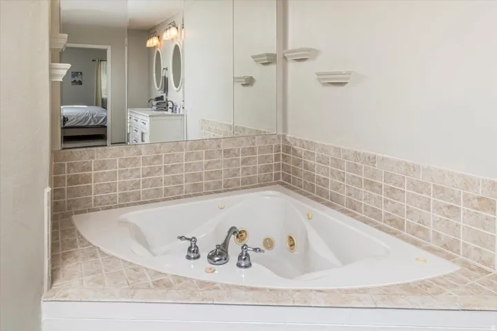 Corner soaking tub with polished chrome fixtures and tile surround