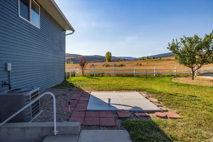Expansive outdoor area featuring a concrete patio, brick paver accents, and a wide grassy yard