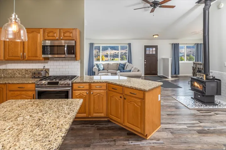 Open-concept living space featuring a kitchen with light wood cabinetry, granite-finish countertops, and stainless steel appliances