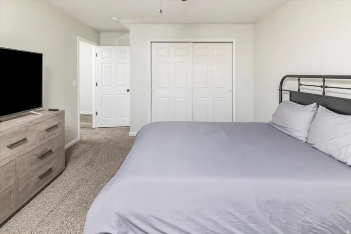 Bedroom featuring light neutral wall paint, textured carpet flooring, and white bifold closet doors