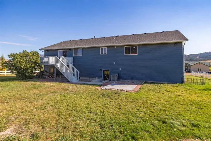 Rear exterior with blue siding and a dark shingle roof