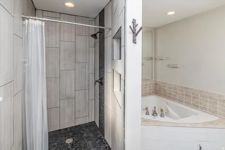 Contemporary shower with large format wood-finish tile, pebble floor, and matte black fixtures