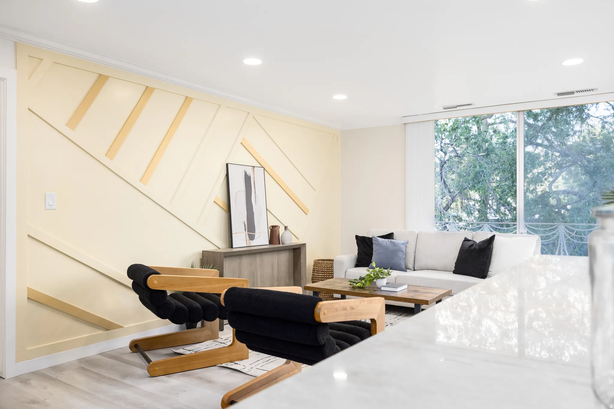 Living area featuring a geometric accent wall, recessed lighting, wood-finish flooring, and expansive windows
