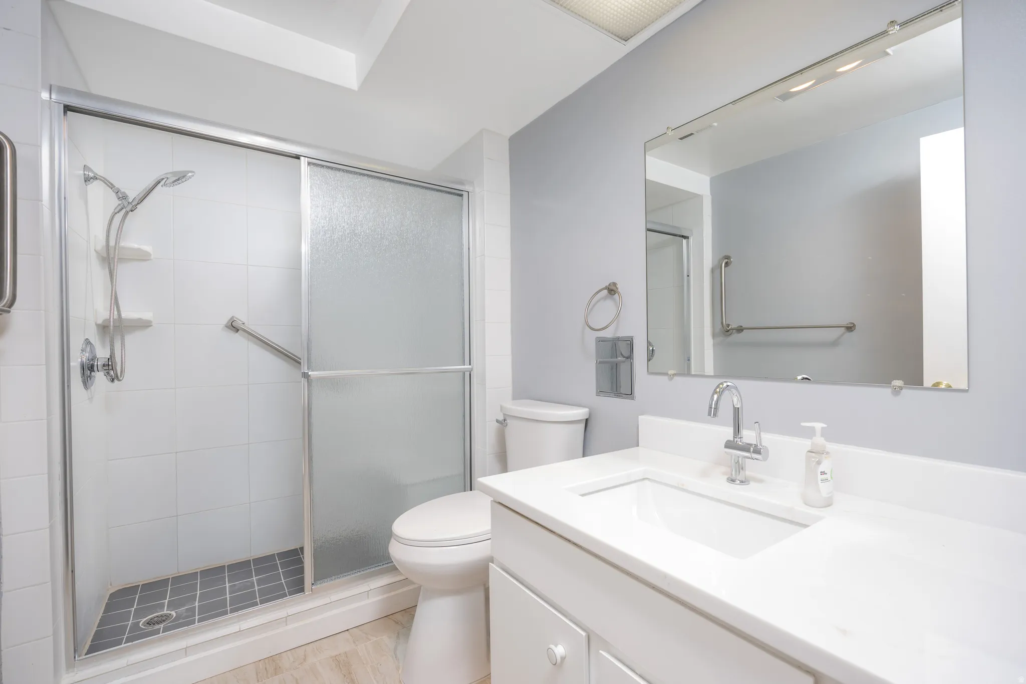 Full bathroom featuring a white vanity with integrated sink, chrome faucet, and a large mirrored wall