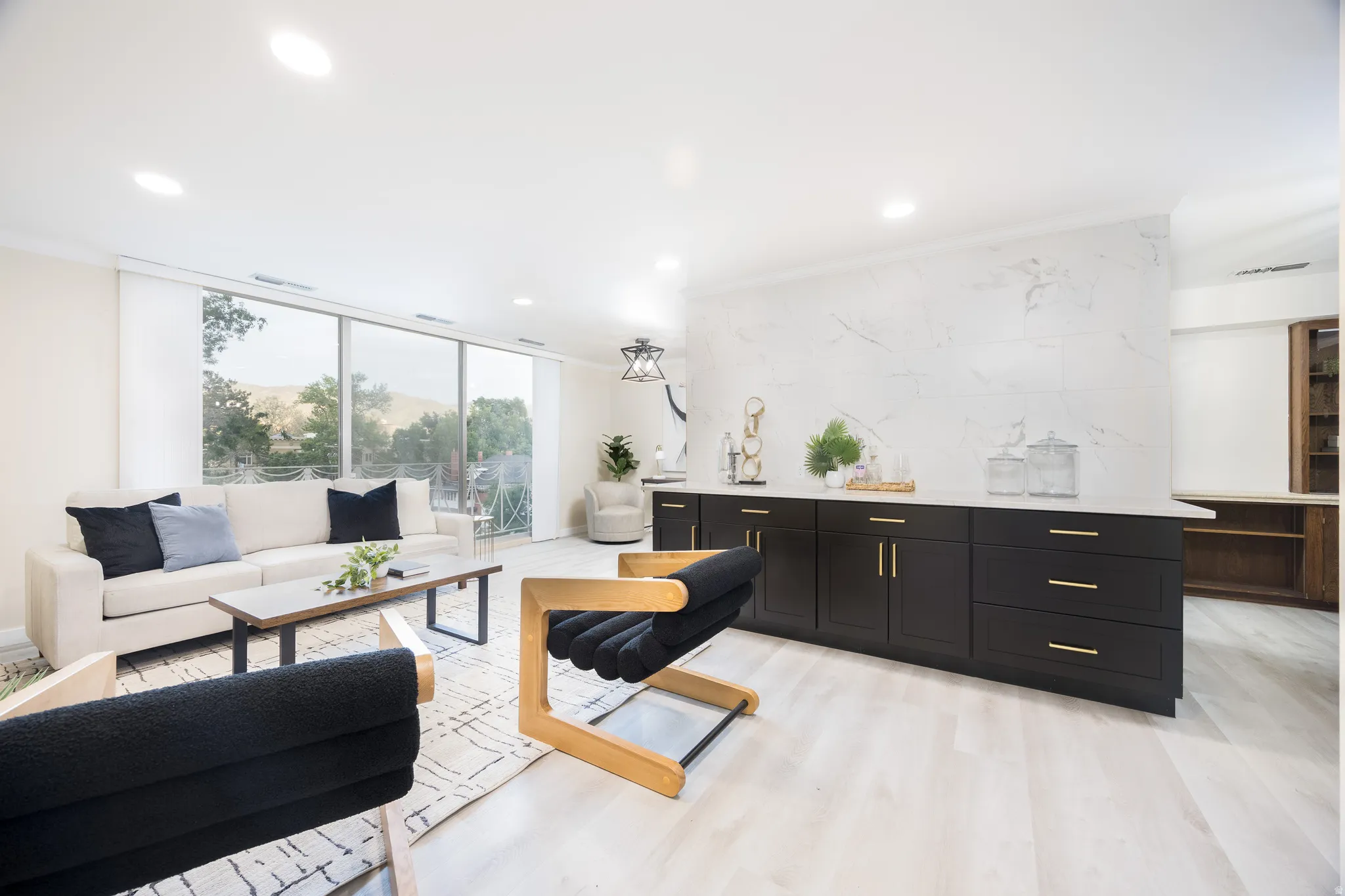 Open-concept living area featuring light wood-finish flooring, recessed lighting, and a full wall of sliding glass panels
