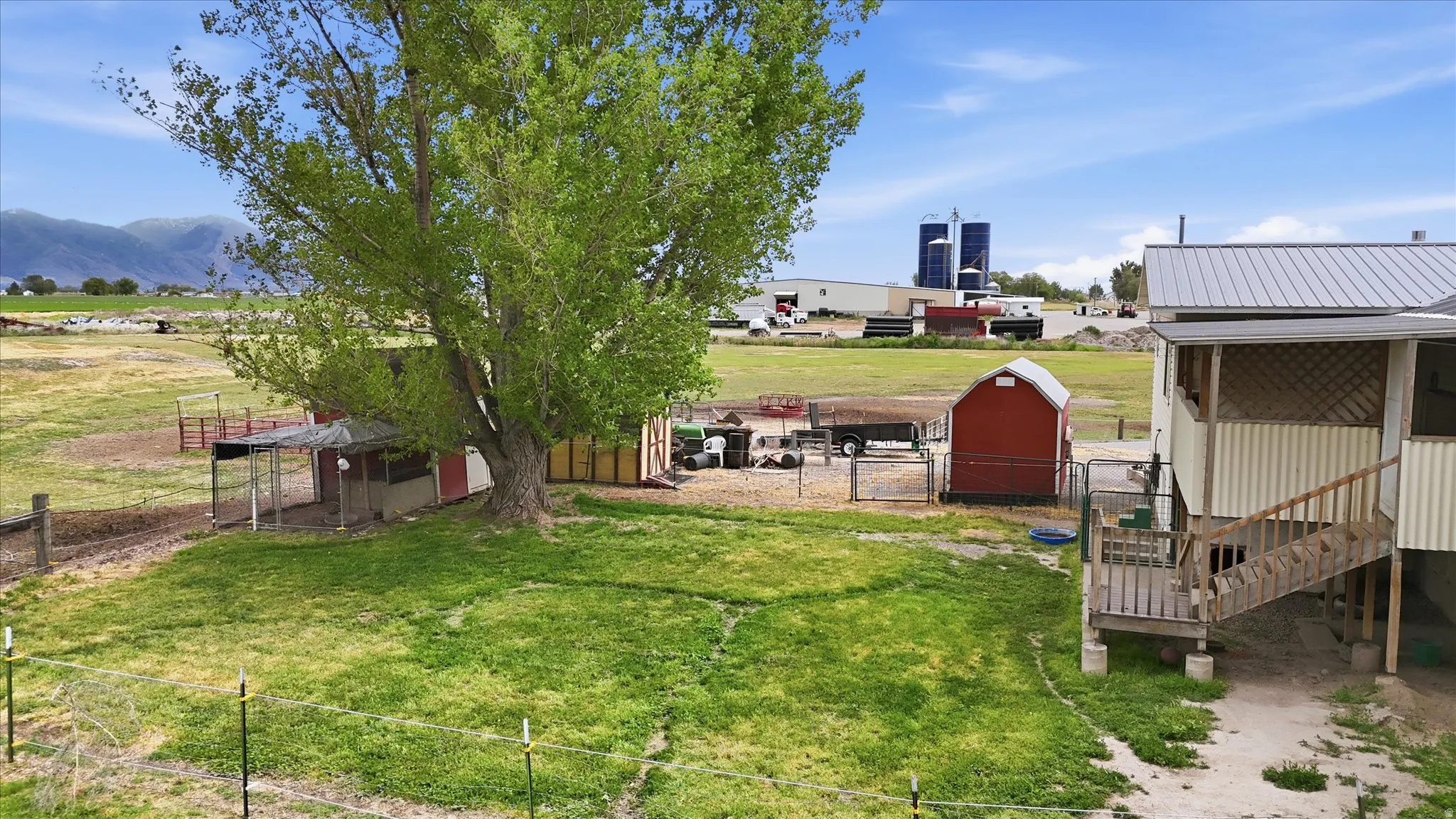 Expansive property featuring a mature tree and red storage shed