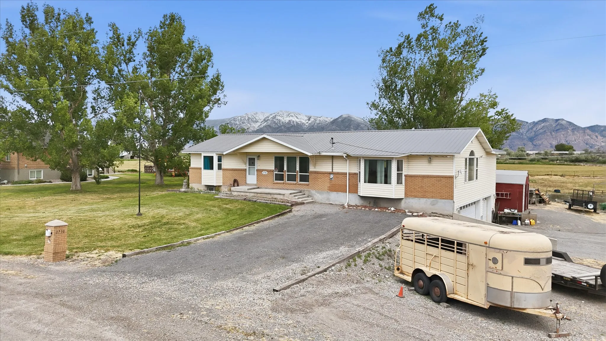 Brick and siding, a covered entry, and a gravel driveway
