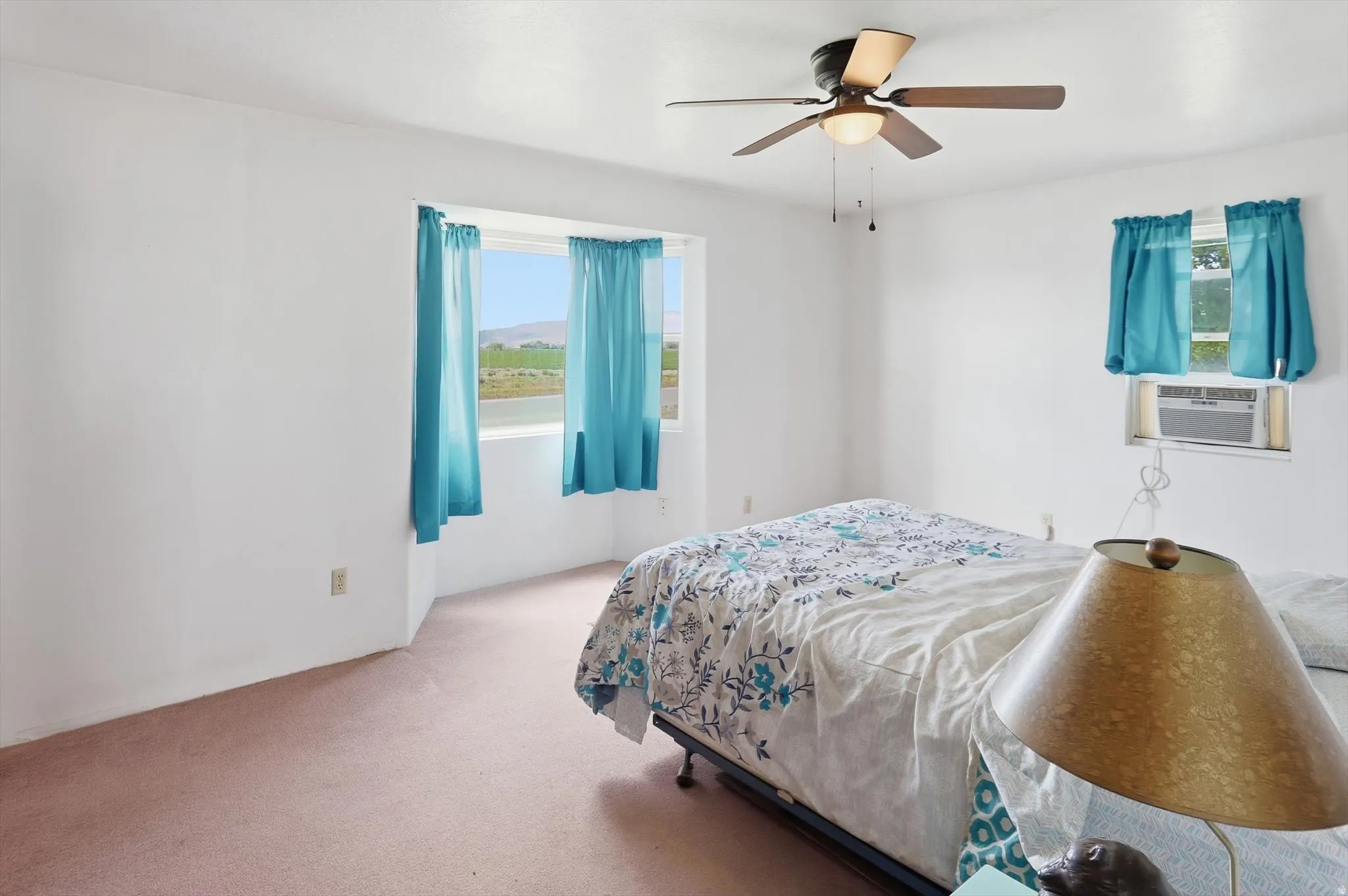 Room featuring a multi-paned bay window, beige carpeting, and white walls