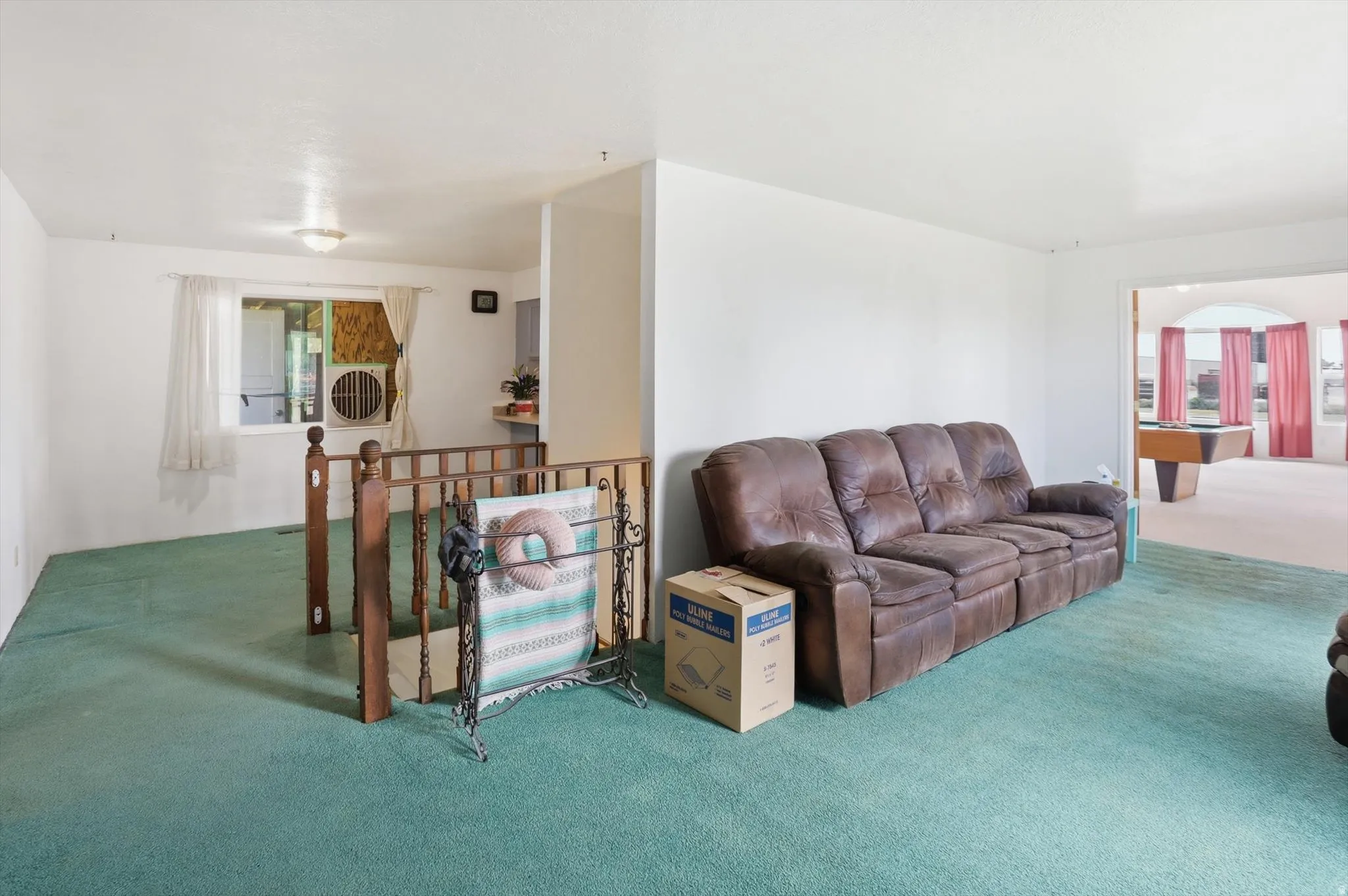 Spacious interior featuring light-toned walls and green carpeting