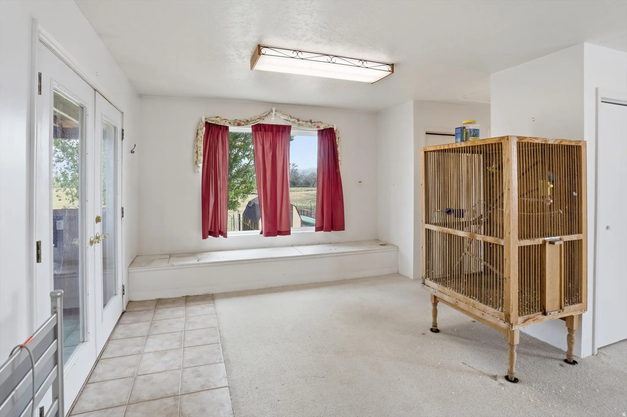 Bright room with white walls and a combination of light-toned tile and carpet flooring